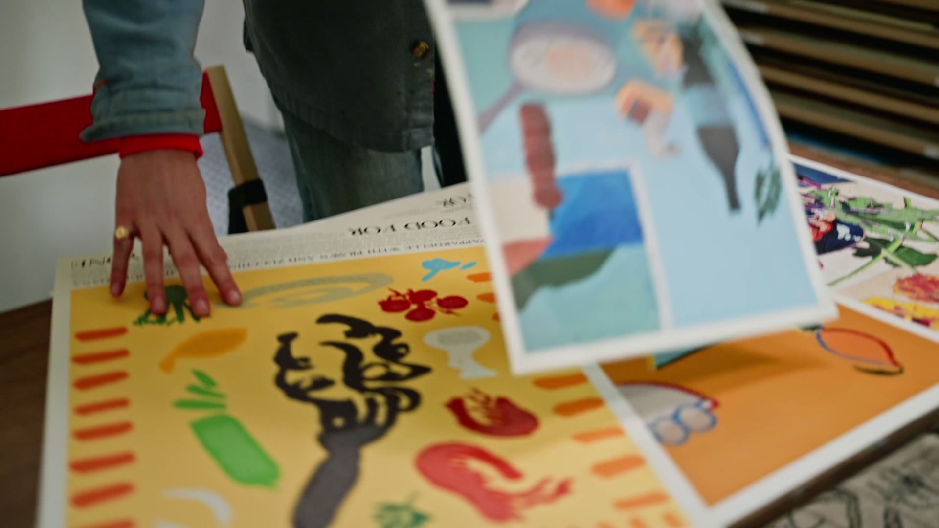 Hands flipping prints on an orange table
